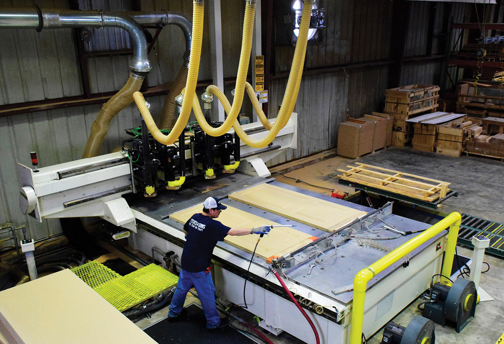 Worker on factory floor operating fiberglass door manufacturing machinery